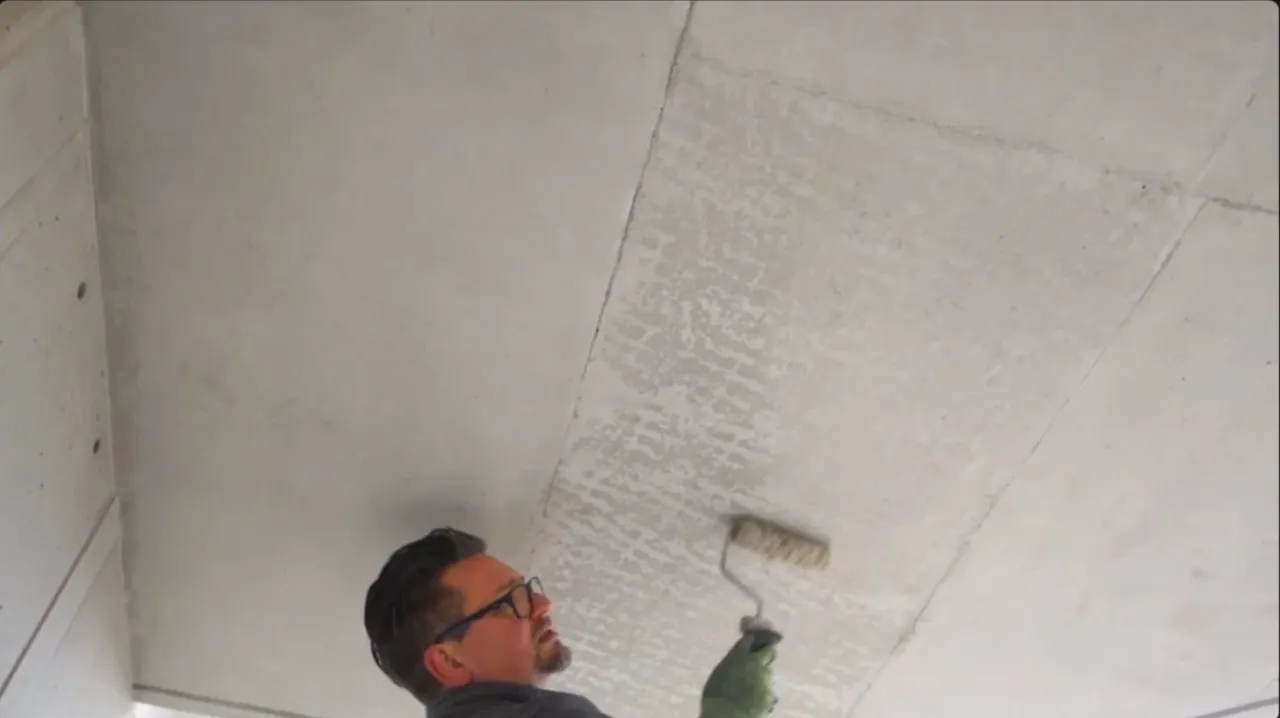 Trainer rollt Betonlasur auf eine Sichtbetondecke