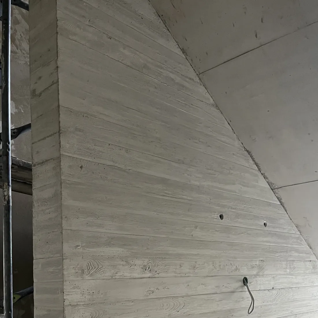 Dieselbe Sichtbetonwand nach der Betonkosmetik: ruhige, gleichmäßige Fläche, die Holzmaserung der Schalung bleibt sichtbar