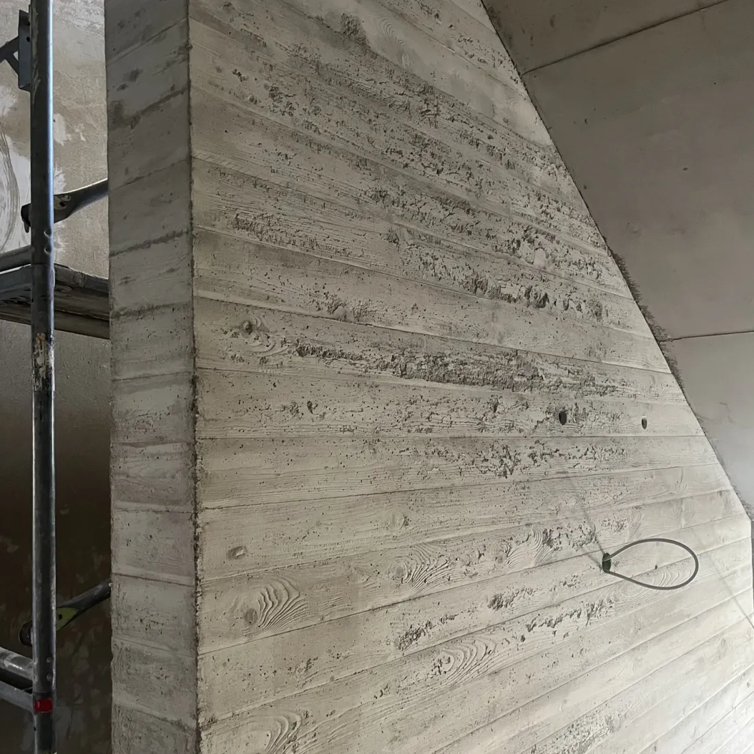 Sichtbetonwand in einem Hotel in Dresden vor der Betonkosmetik: unruhige Fläche mit dunklen Poren und Wolken