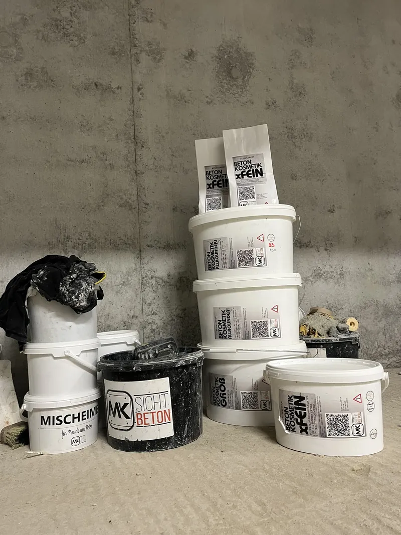 Eimer mit Betonkosmetik-Material vor einer Sichtbetonwand