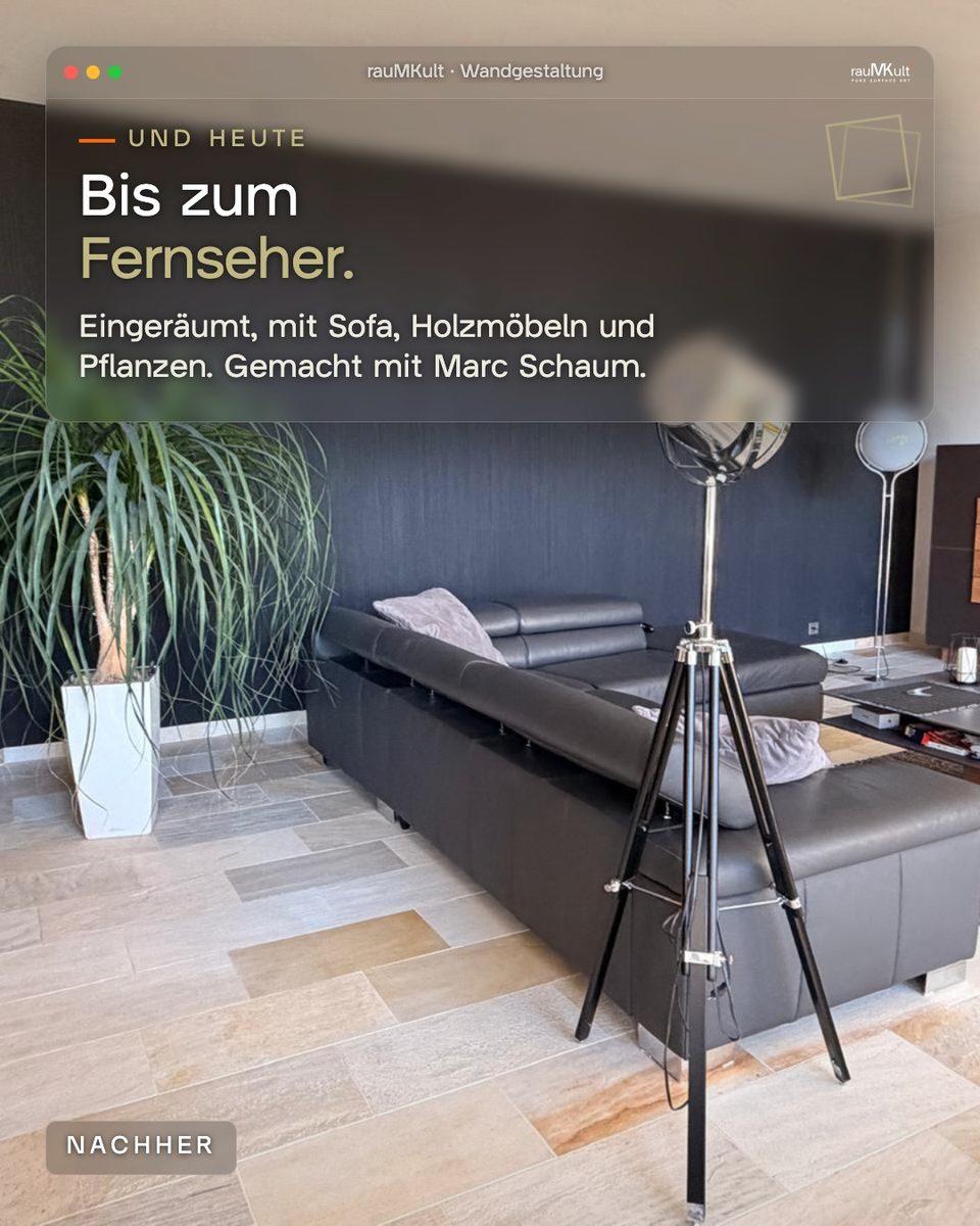 Fernsehseite des eingeräumten Wohnraums mit Sofa, Stehleuchte und Pflanze vor der schwarzen Wand