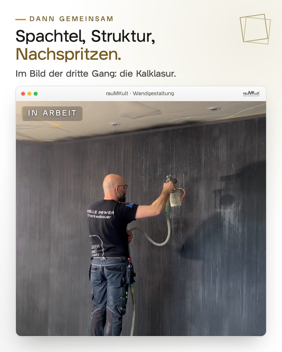 Ein Handwerker von rauMKult spritzt schwarze Kalklasur auf die gerillte Wand