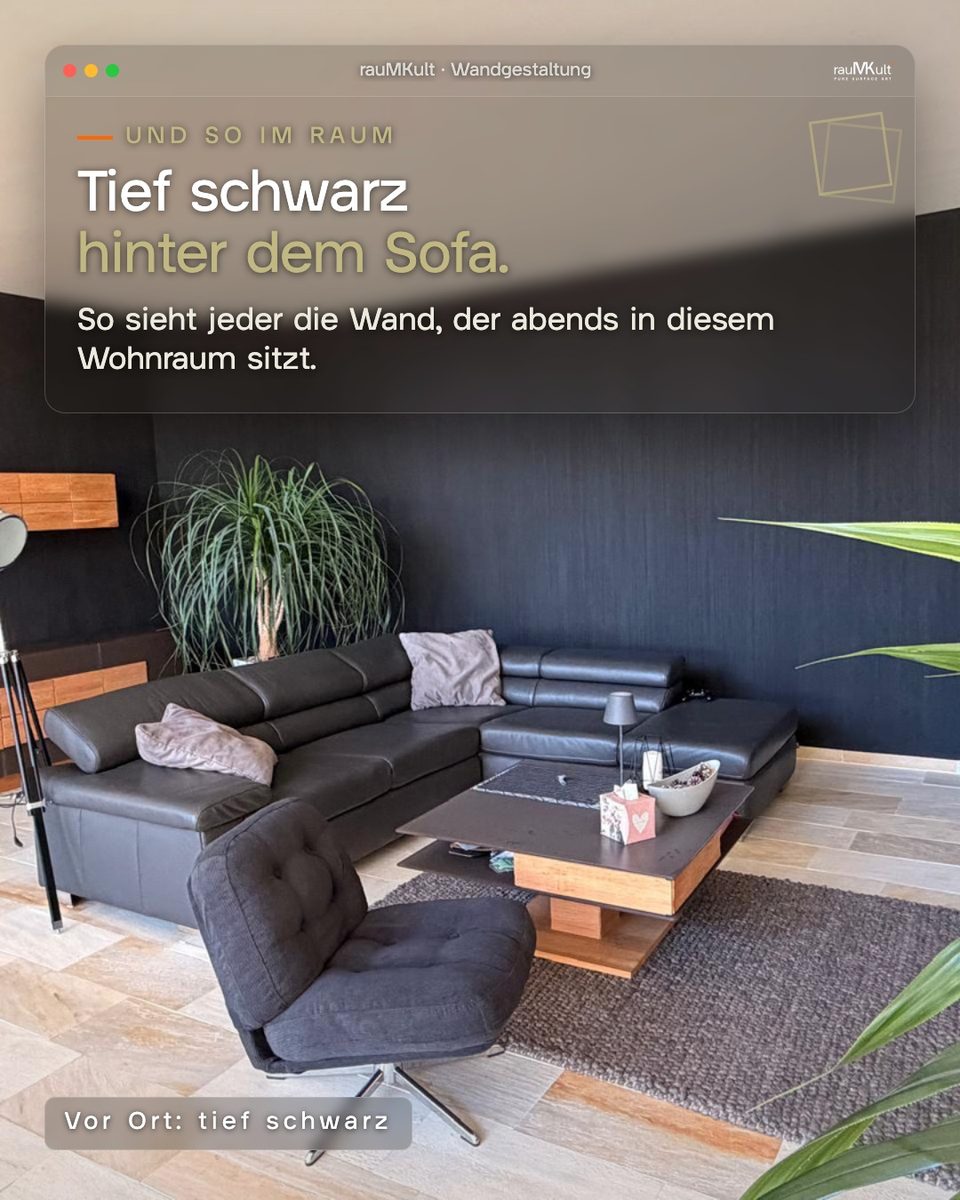Wohnraum mit der schwarzen Designwand hinter dem Ledersofa, so wie man sie abends im Raum sieht