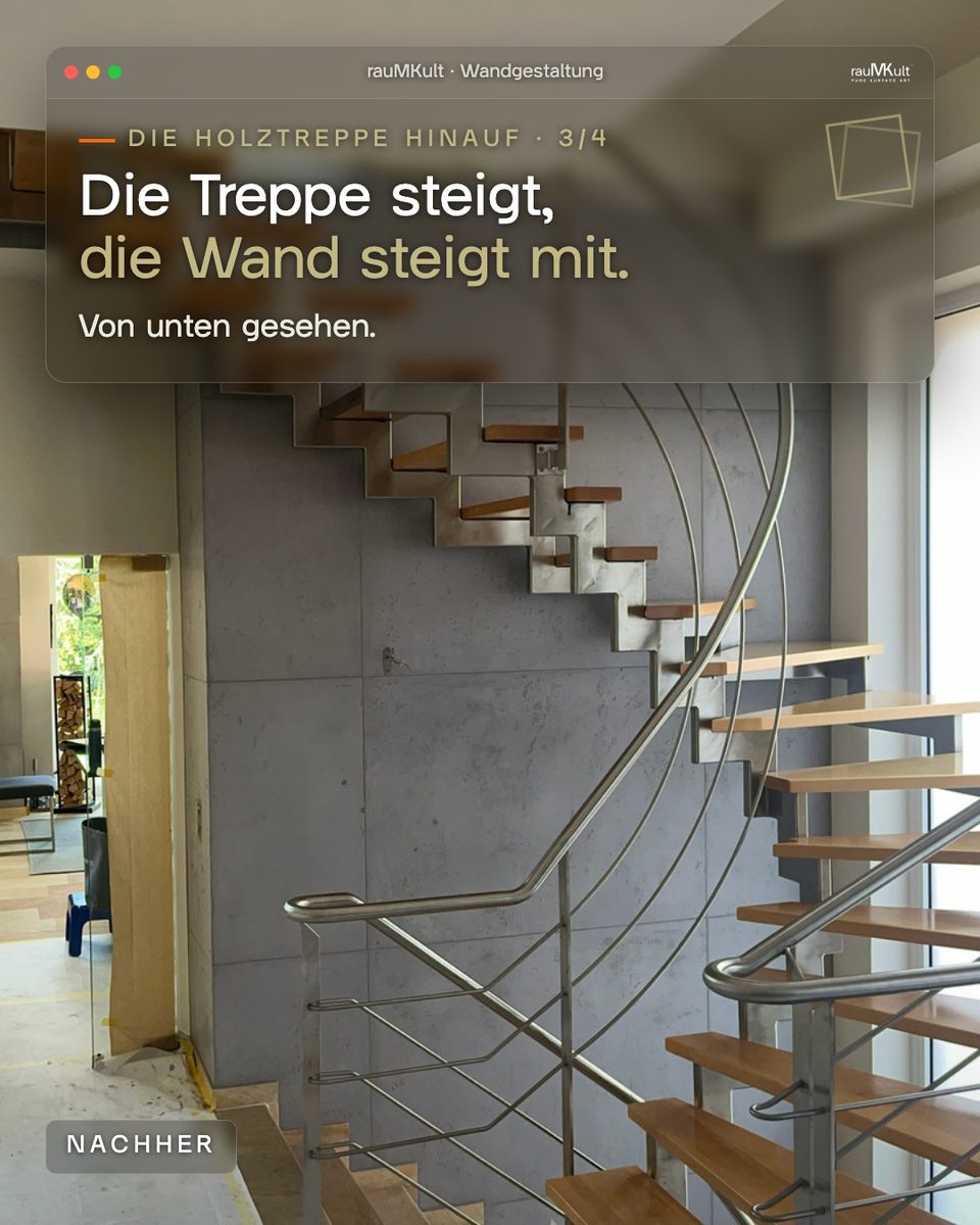 Freitragende Holztreppe mit Edelstahlgeländer von unten gesehen, dahinter steigt die Wand in Betonoptik mit