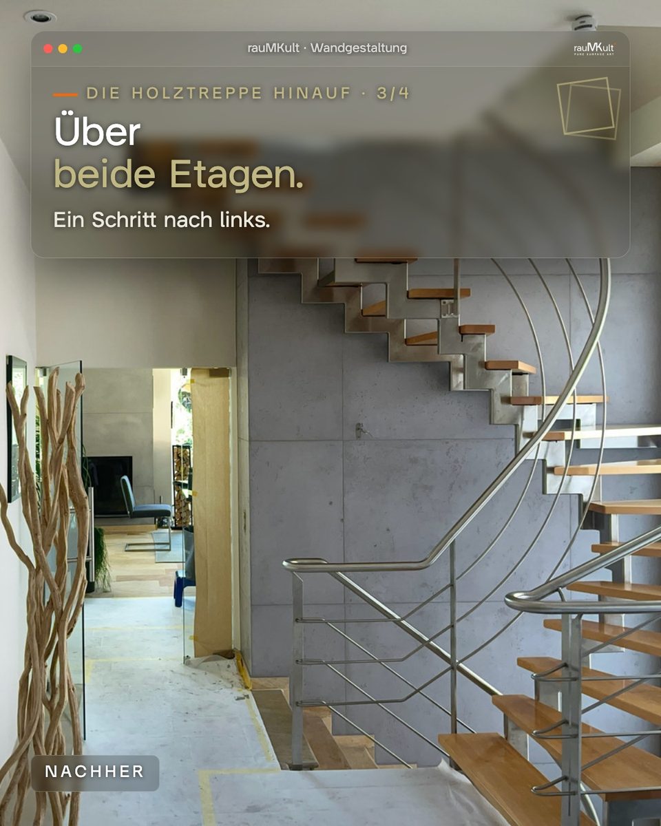 Treppenhaus über beide Etagen mit der Wand in Schalbetonoptik hinter der Holztreppe