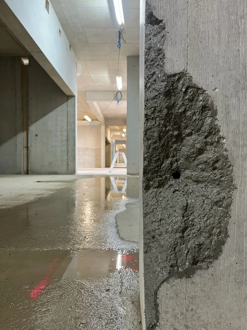 Abplatzung an der Pfeilerkante gereinigt, gestockt und grundiert, dahinter der nasse Flur im Rohbau