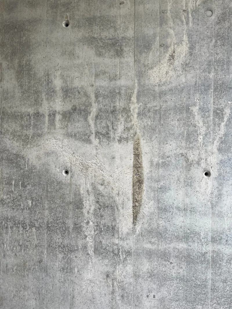 Nahaufnahme der aufgerissenen Betonhaut mit Kiesnestern, die Holzbrettstruktur ist kaum noch zu erkennen