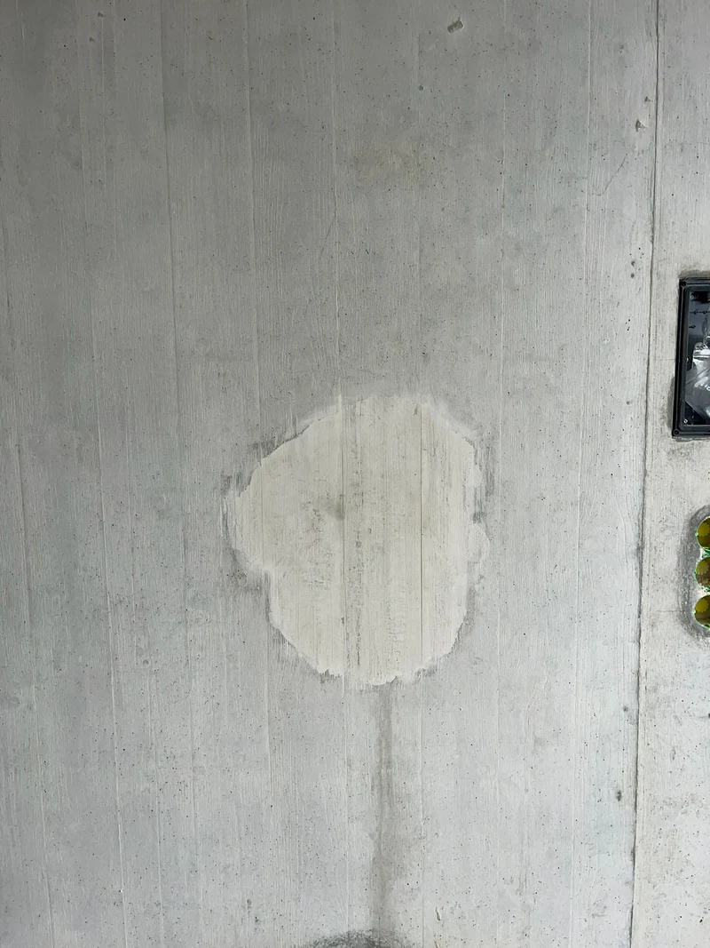 Gefüllte Abplatzung getrocknet und hell, ihre Form ist auf der glatten Betonfläche noch deutlich zu sehen