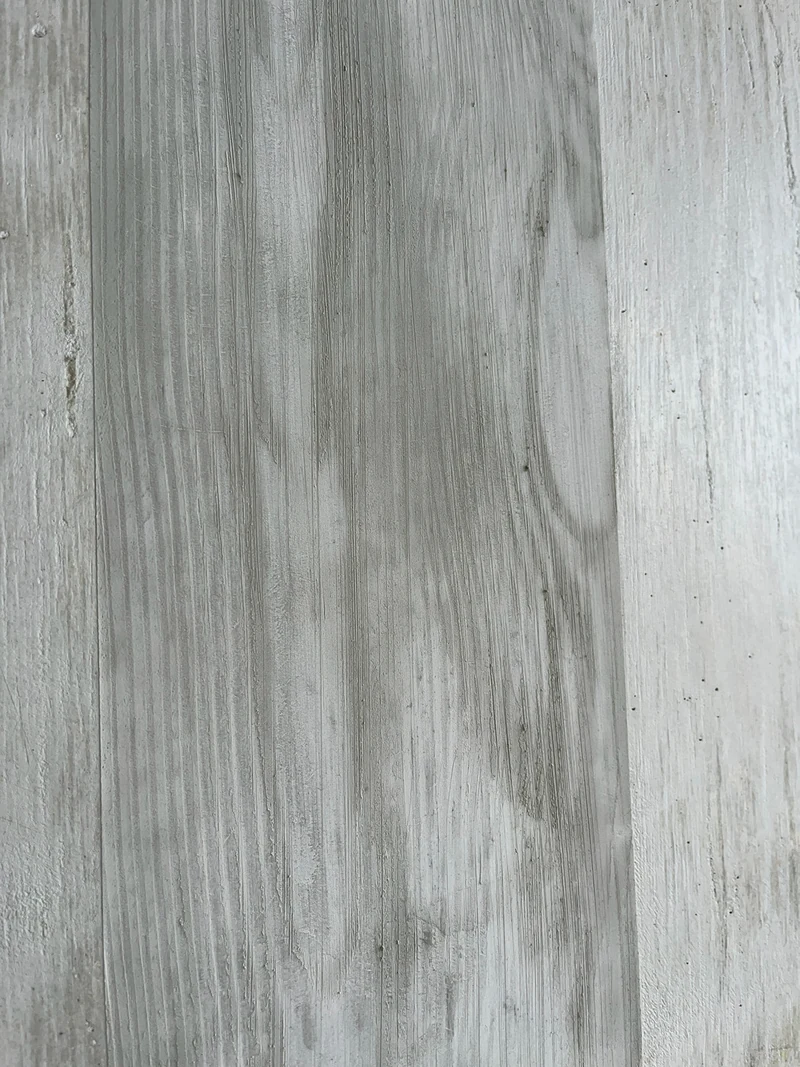 Nahaufnahme eines Bretts mit nachgebildeter Holzmaserung in Wellen auf der reparierten Sichtbetonwand