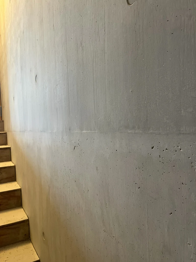 Ganzer Treppenaufgang mit Holzstufen nach der Retusche, Sichtbetonwand im gleichmäßigen Grauton