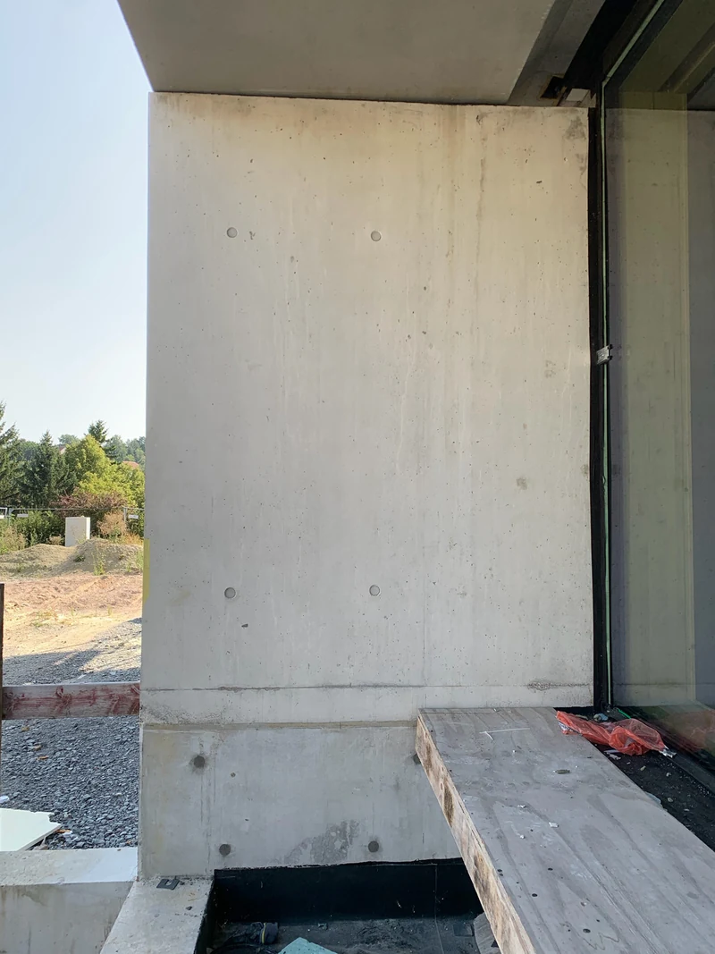 Außenwand aus Sichtbeton mit einem Streifen in der Mitte, der sich vor der Arbeit deutlich abzeichnet