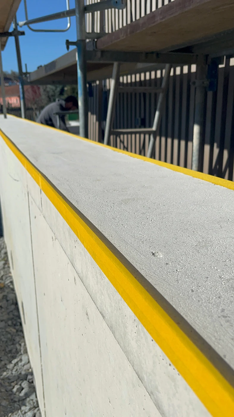 Geschliffene Mauerkrone mit gelbem Klebeband an beiden Seiten als Schutz für den Sichtbeton darunter
