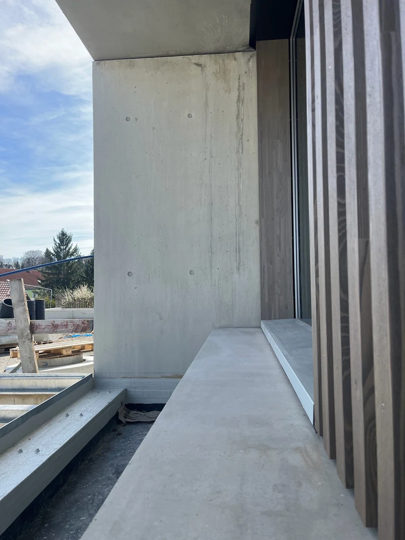 Außenwand acht Monate nach der Reparatur, vorne die lange Betonmauer an der Fassade