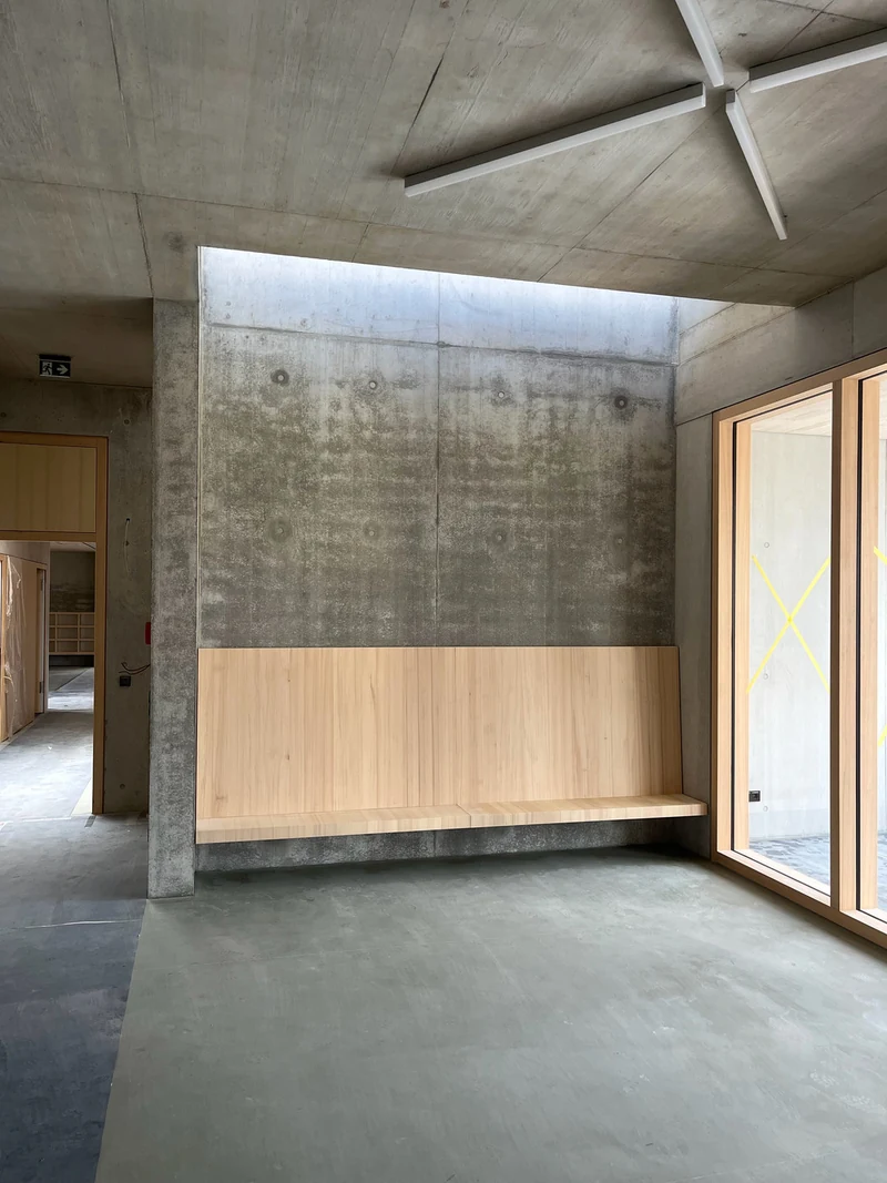 Innenwand aus Sichtbeton über einer Holzgarderobe, dunkel und wolkig mit deutlichen Abzeichnungen