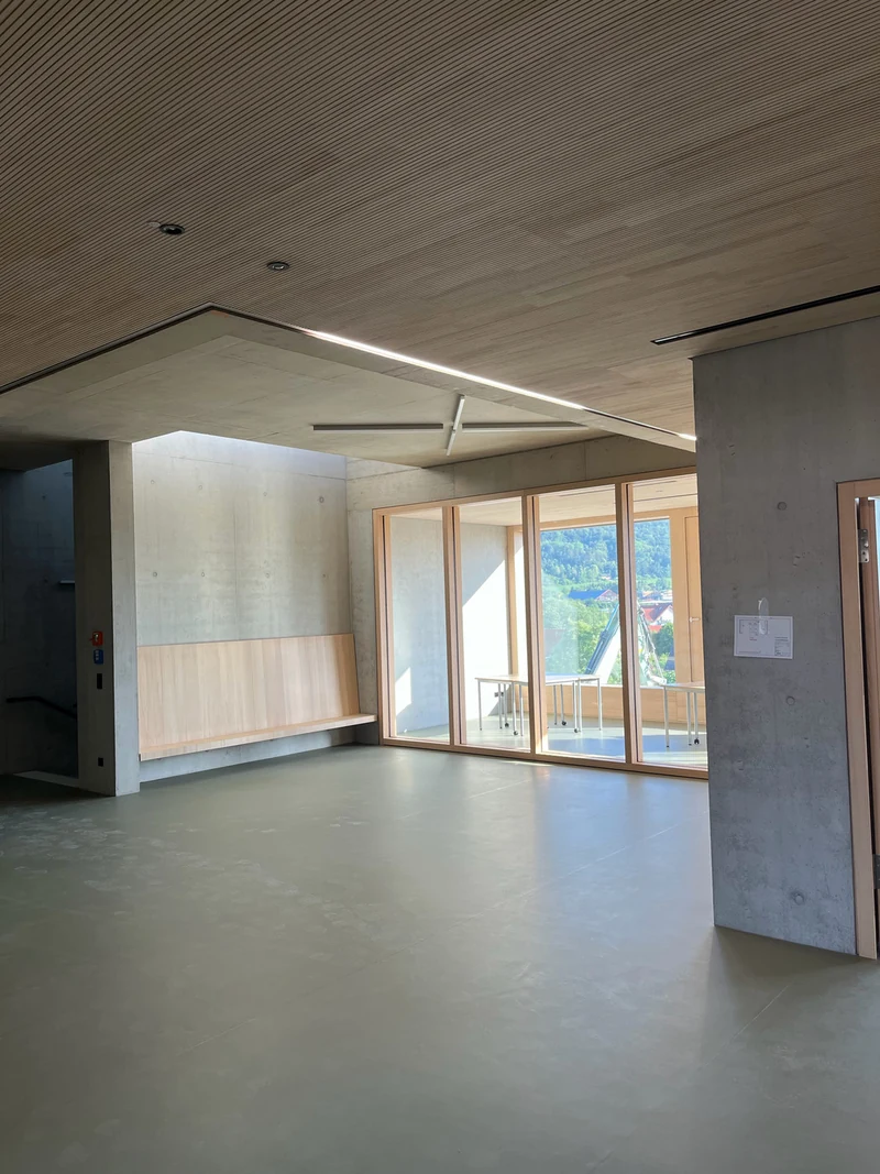Raum mit Sichtbetonwänden, Holzdecke und Fensterfront zwei Monate nach der Retusche, Wand getrocknet