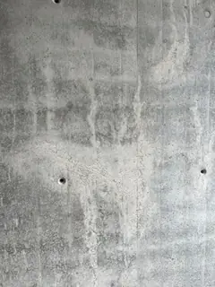 Wandfläche mit hellen Auswaschungen, senkrechten Läufern und kleinen Lunkern im Sichtbeton