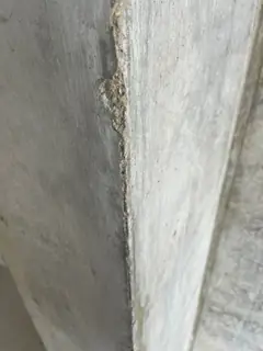 Beschädigte Betonkante mit kleinen Ausbrüchen und hellem Abrieb entlang der Ecke