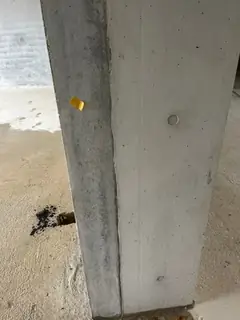 Betonstütze mit gelber Klebemarkierung und einem Ankerkonus, am Boden eine dunkle Stelle