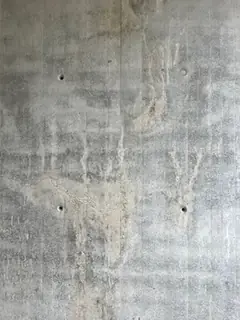 Sichtbetonwand mit hellen Läufern, in der Mitte eine hellere, verschmierte Stelle wie nachbearbeitet