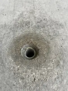 Spindelloch mit dunklem Hof und rissiger, abblätternder Oberfläche unterhalb der Öffnung