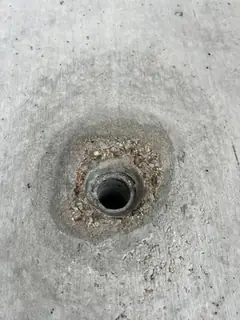 Spindelloch, das von einem Kiesnest mit freiliegenden Steinchen und lockerem Material umgeben ist