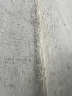 Senkrechte Schalungsfuge mit leichtem Grat und vielen kleinen Lunkern in der angrenzenden Betonfläche