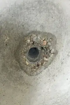 Spindelloch mit Kiesnest, freiliegende Steinchen im ausgebrochenen Ring um die Öffnung