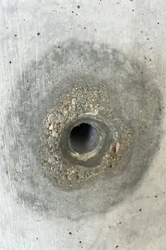 Spindelloch, umgeben von einem Ring aus freiliegendem Kies und grobem Mörtel, dazu ein dunkler Hof