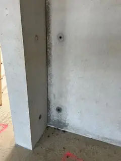 Innenecke aus Betonstütze und Wand mit zwei Ankerlöchern, am Boden rosa Markierungen