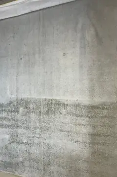 Sichtbetonwand mit waagerechtem Übergang zu einem dunkleren Betonierabschnitt, oben eine Decke