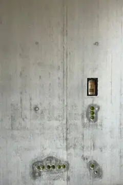 Sichtbetonwand mit einer Reihe Elektrodosen in einer ausgebluteten Mulde, darüber ein Schalter mit Etikett