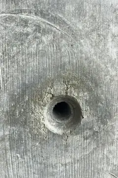 Spindelloch mit krümeligem Rand und dunklem Hof, im Hintergrund eine feine Brettmaserung