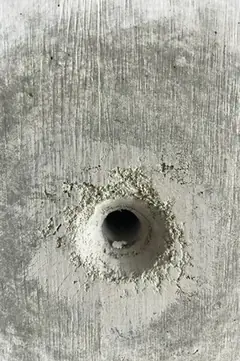 Spindelloch mit weißlichem, krümeligem Ausbruchring und senkrechter Brettmaserung in der Umgebung