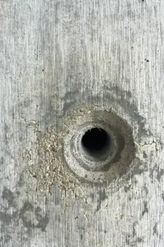 Spindelloch mit abgesandetem, hellem Bereich links daneben und breitem Ring um die Öffnung