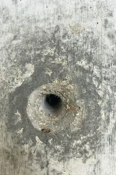 Spindelloch mit rostfarbenem Rand und feinem Riss, der von der Öffnung nach unten verläuft