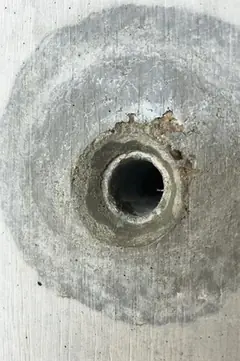 Spindelloch mit kleinem Ausbruch am oberen Rand in einem sehr großen, hell umrandeten dunklen Hof