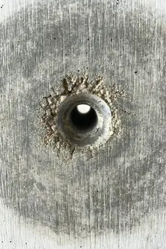 Durchgehendes Spindelloch mit krümeligem Rand, durch das Licht fällt, in großem dunklem Hof
