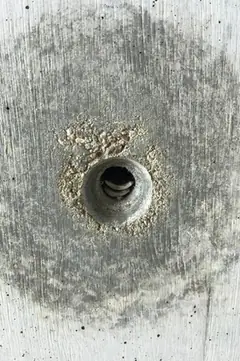 Spindelloch mit hellem, krümeligem Ausbruchring und dunklem Kern in einem großen runden Hof