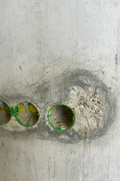 Elektrodosen am Bildrand, rechts daneben eine rau ausgeblutete, helle Stelle mit dunklem Rand im Sichtbeton