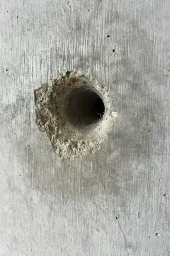 Spindelloch mit hellem, sandigem Ausbruch links oben und kleinem rostigem Fleck am Rand