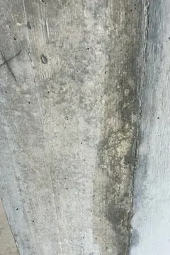 Schräge Betonkante mit dunklem, rauem Streifen entlang der Ecke, daneben glatte helle Fläche