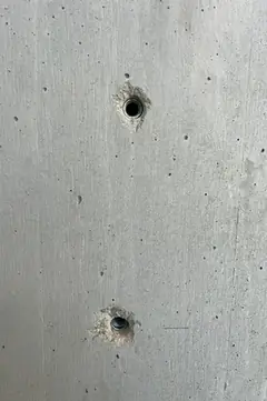 Zwei Spindellöcher mit dunklen Kunststoffrohren übereinander, das untere mit kleinem Ausbruch am Rand