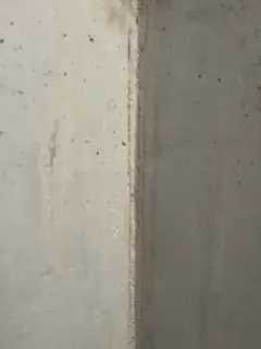 Senkrechte Betonkante mit hellem Zementleimstreifen und kleinen Lunkern in den angrenzenden Flächen