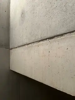Schräg ansteigende Treppenwange aus Sichtbeton mit durchgehender Fuge, die Fläche ist glatt und hell