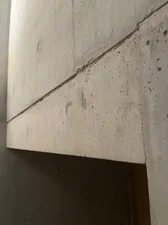 Treppenwange mit schräg verlaufender Fuge und Abschluss an einer Öffnung, links eine dunkle Wandfläche