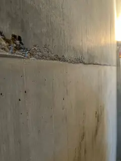 Kiesnest mit freiliegenden Steinen am linken Rand einer waagerechten Betonierfuge, darunter eine glatte Fläche