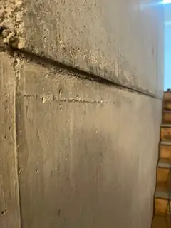 Schräg verlaufende Betonierfuge mit rauer Zone links oben und senkrechter Fuge, rechts Holzstufen