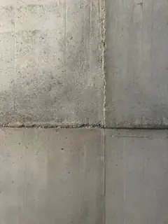 Kreuzung einer waagerechten und einer senkrechten Fuge in der Wand, die obere Hälfte wirkt grobkörniger