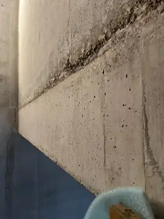 Schräge Betonierfuge mit dunkler, rauer Zone, unten rechts ein blauer Schaumstoffkeil auf Karton
