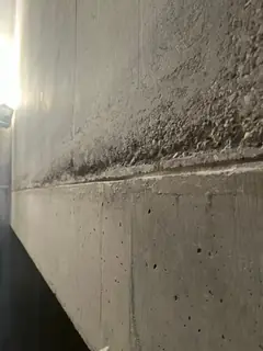 Breites Kiesnest mit grobem Korn oberhalb einer Fuge, darunter eine glatte Fläche mit kleinen Lunkern